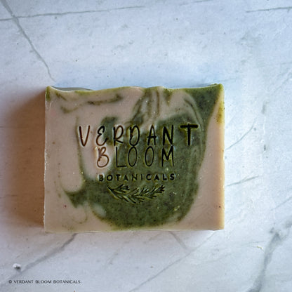 Hand‑cut Still Pines tallow soap bar in a green‑gray hue with natural clay texture and subtle botanical speckling.