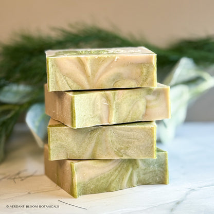 Hand‑cut Still Pines tallow soap bar in a green‑gray hue with natural clay texture and subtle botanical speckling.